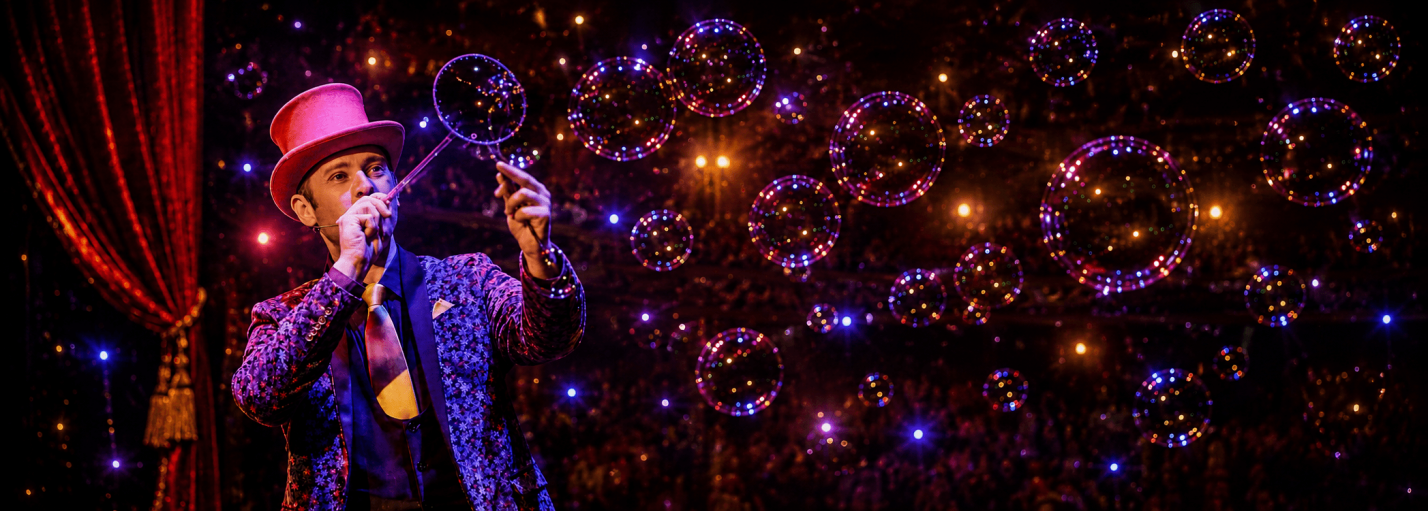 Allan Hart soufflant des bulles de savon sur scène lors de son spectacle